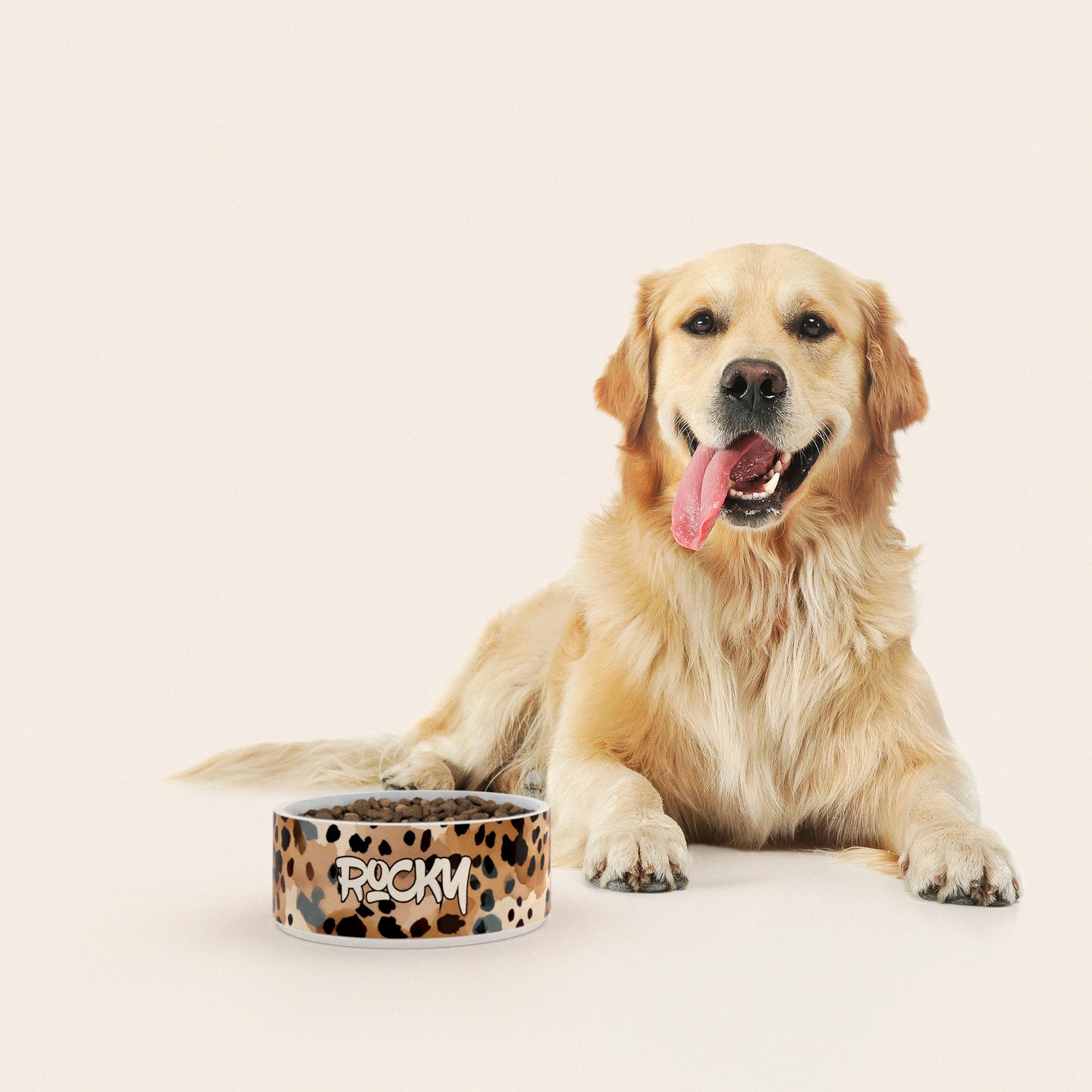 Un golden retriever assis à côté d'un bol pour chien au motif Leopard personnalisé avec le nom ROCKY