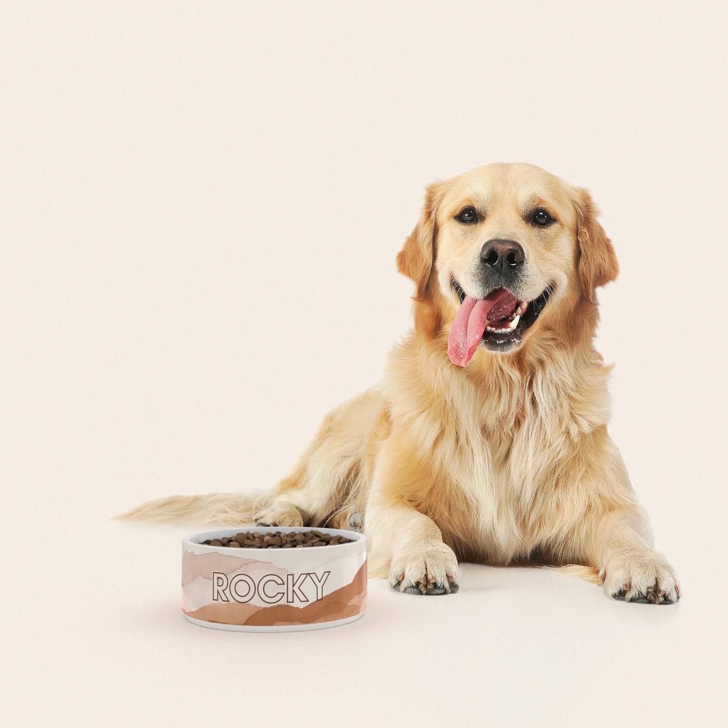 Un golden retriever assis à côté d'un bol pour chien au motif Dunes personnalisé avec le nom ROCKY