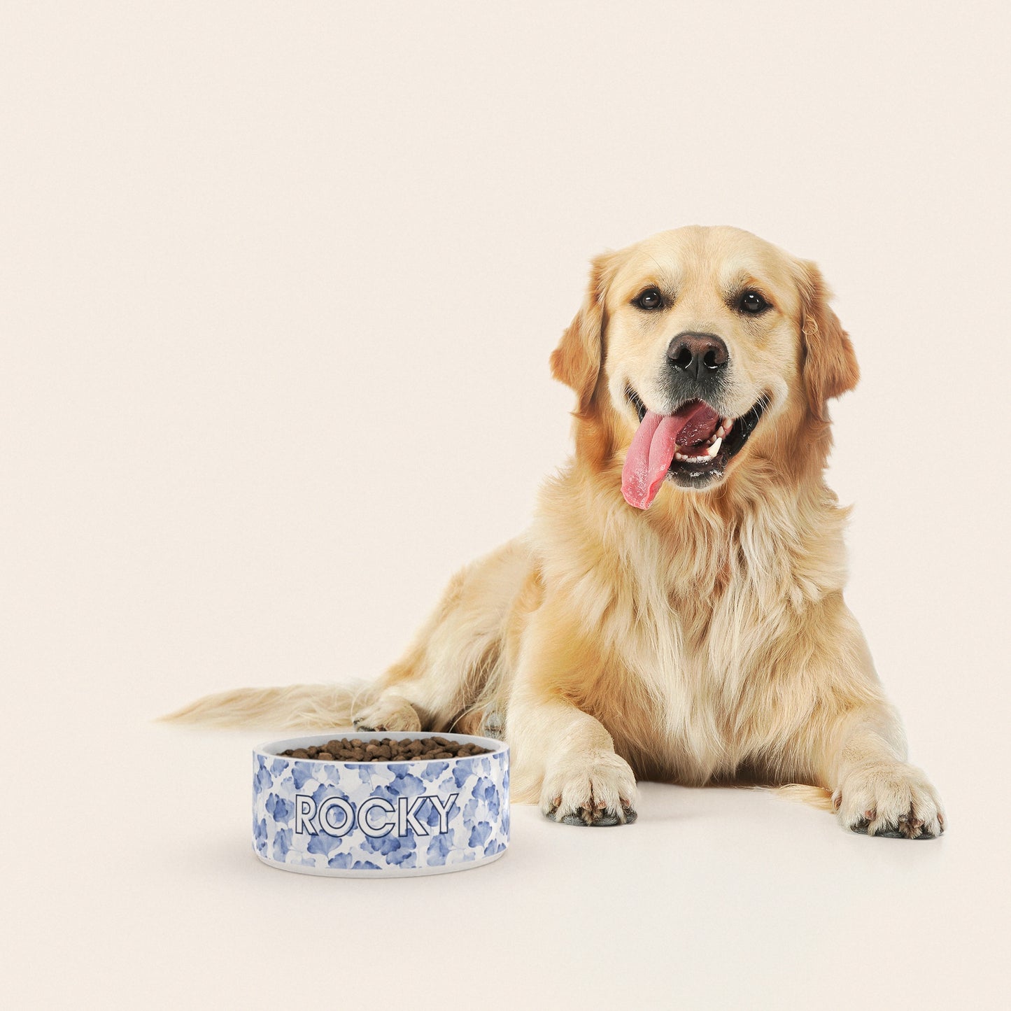 Un golden retriever assis à côté d'un bol pour chien au motif Ginkgo Bleu personnalisé avec le nom ROCKY