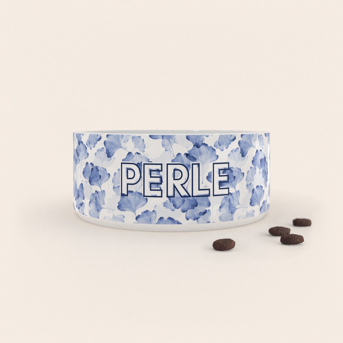 Gamelle pour chien au motif Ginkgo Bleu personnalisés avec le nom Perle, accompagné de croquettes sur fond neutre.