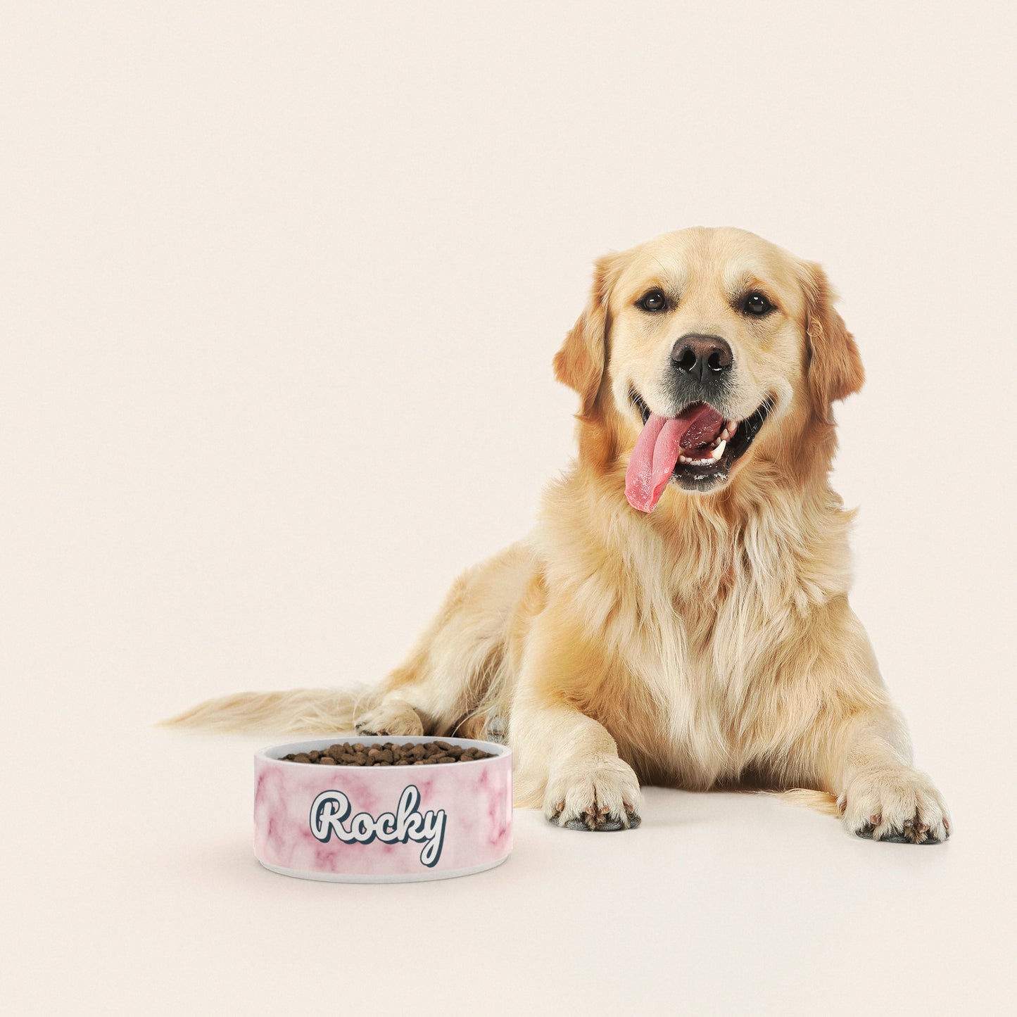 Un golden retriever assis à côté d'un bol pour chien au motif Marbre Rose personnalisé avec le nom ROCKY